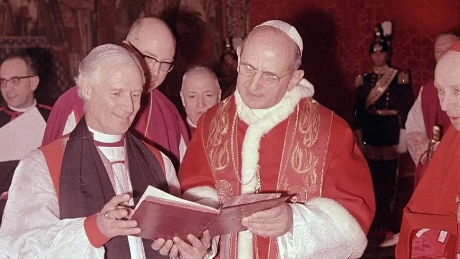 Bishop John Moorman, leader of the Anglican delegation at the Second Vatican Council, examines a book with Pope Paul VI. Archbishop Jan Willebrands peers over Moorman's shoulder, while Cardinal Augustin Bea watches from the pope's side