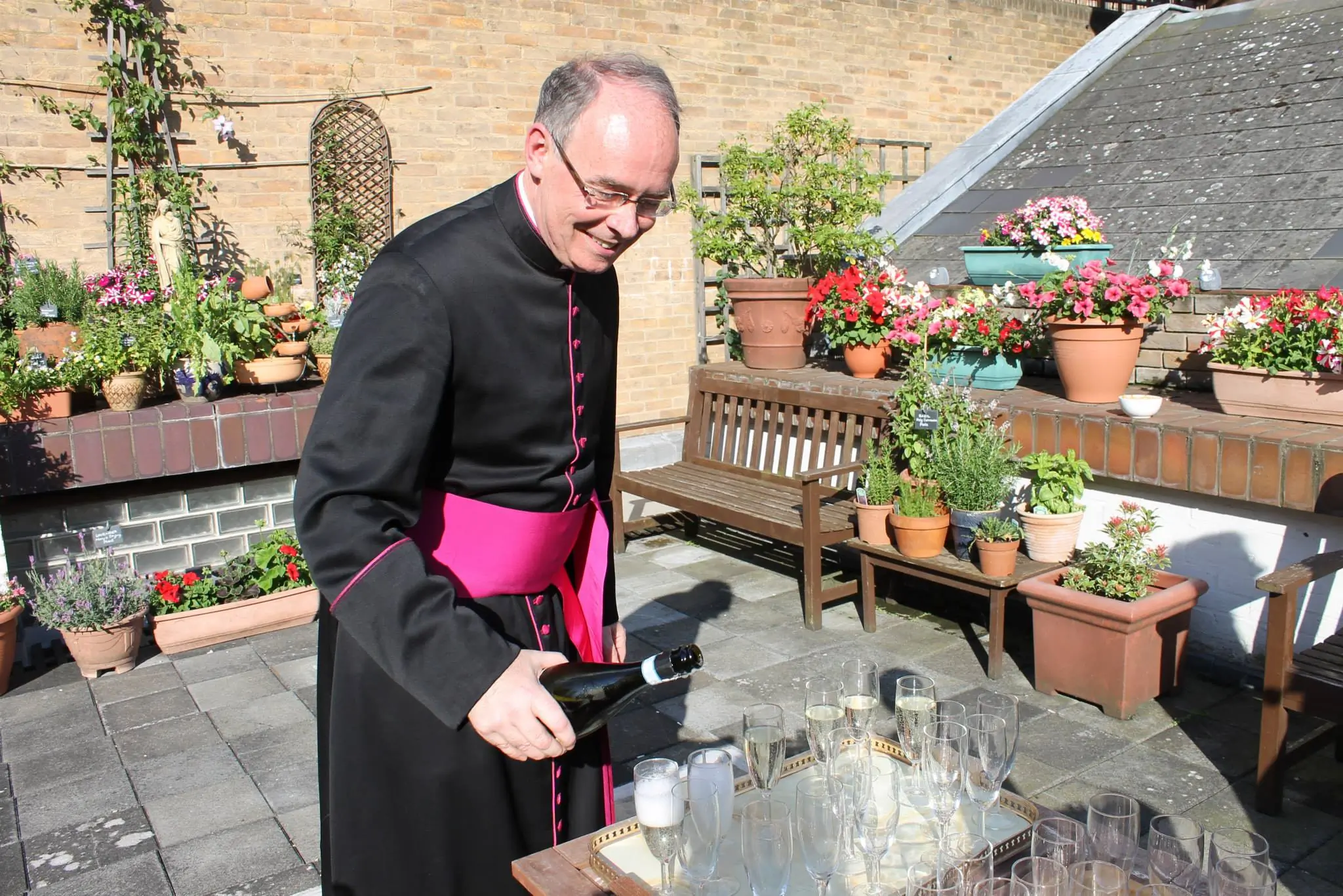 Msgr. Mark Langham pouring Prosecco on the Fisher House terrace