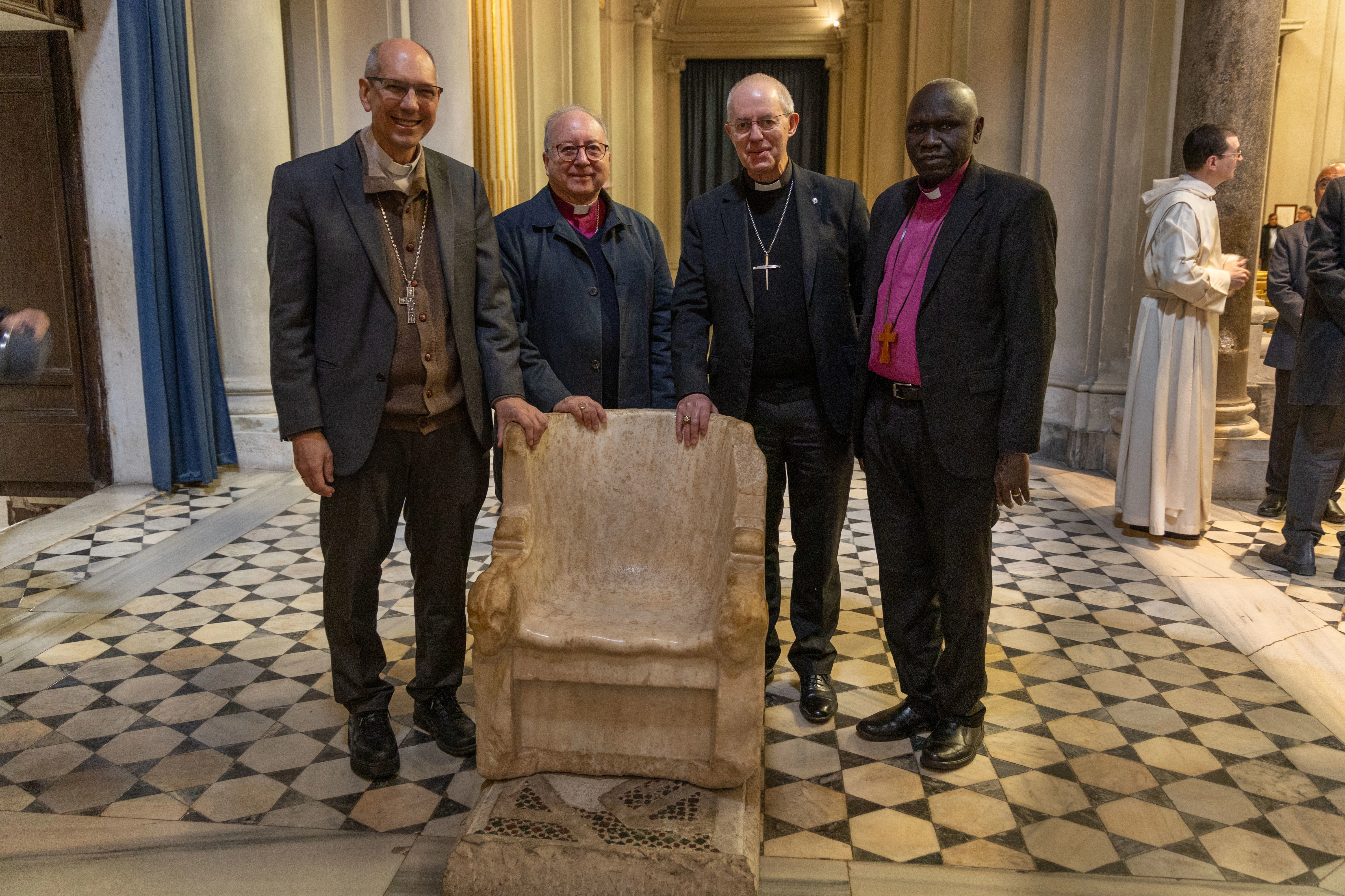 During the IARCCUM Summit visit to San Gregorio al Celio, Archbishop Donald Bolen, Bishop David Hamid, the Archbishop of Canterbury Justin Welby, and Bishop Anthony Poggo stand beside the Chair of Gregory the Great