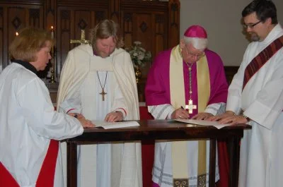 Bishop Gregory Kerr-Wilson and Archbishop Daniel Bohan sign a covenant between the Anglican Diocese of Qu'Appelle and the Archdiocese of Regina during an ecumenical service at St. Paul's Anglican Cathedral in Regina. The two bishops are assisted by deacons Susan Page and Joe Lang