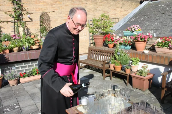 Msgr. Mark Langham pouring Prosecco on the Fisher House terrace