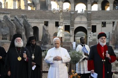 Pope Leo XIV attends an ecumenical Christian prayer service inside Rome's Colosseum, before joining representatives of other religions outside to appeal for peace. The pope is standing between Greek Orthodox Patriarch Theodore II of Alexandria and Catholicos Awa III, patriarch of the Assyrian Church of the East