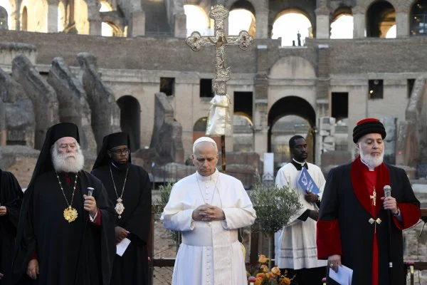 Pope Leo XIV attends an ecumenical Christian prayer service inside Rome's Colosseum, before joining representatives of other religions outside to appeal for peace. The pope is standing between Greek Orthodox Patriarch Theodore II of Alexandria and Catholicos Awa III, patriarch of the Assyrian Church of the East