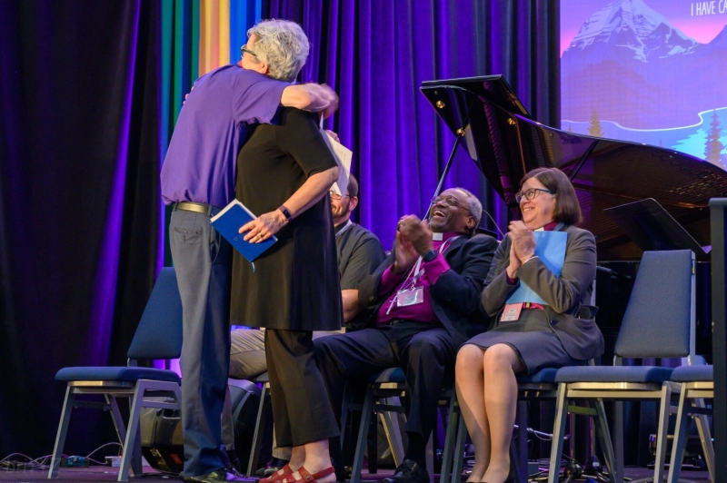 Archbishop Fred Hiltz embraces National Bishop Susan Johnson of the Evangelical Lutheran Church in Canada, while Episcopal Church Presiding Bishop Michael Curry and Evangelical Lutheran Church of America Presiding Bishop Elizabeth Eaton applaud